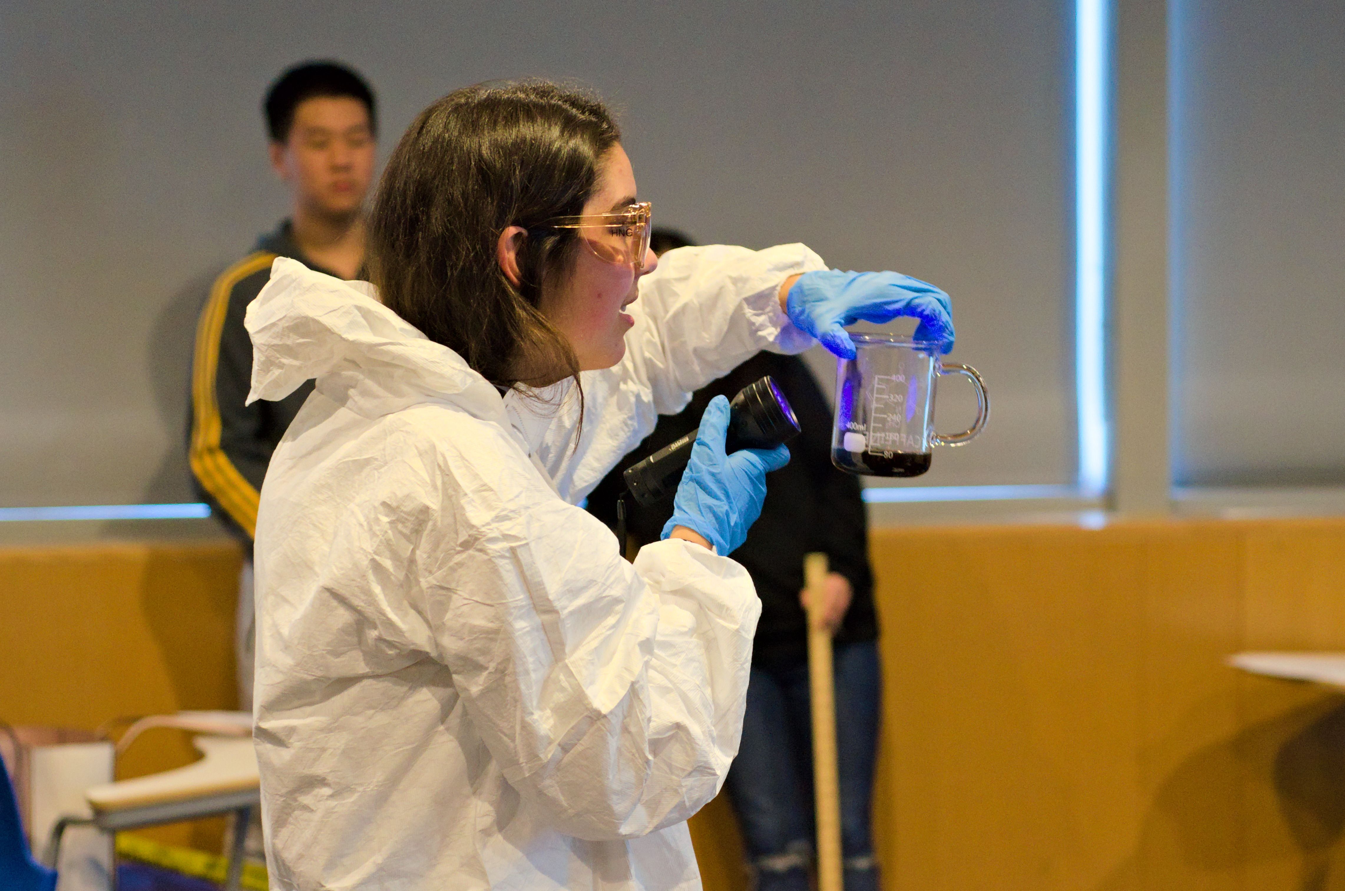 Teacher demonstrates optical properties of a chemical with a blacklight